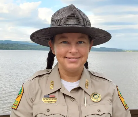 Sasha Bowles - Lake Dardanelle Interpreter pictured dressed in uniform in front of a lake