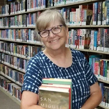 Ellen McWhirter holding a stack of books