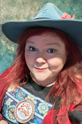 Red haired white woman in a blue hat 