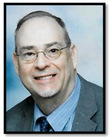 Older White Man in grey suit with blue shirt on a blue background