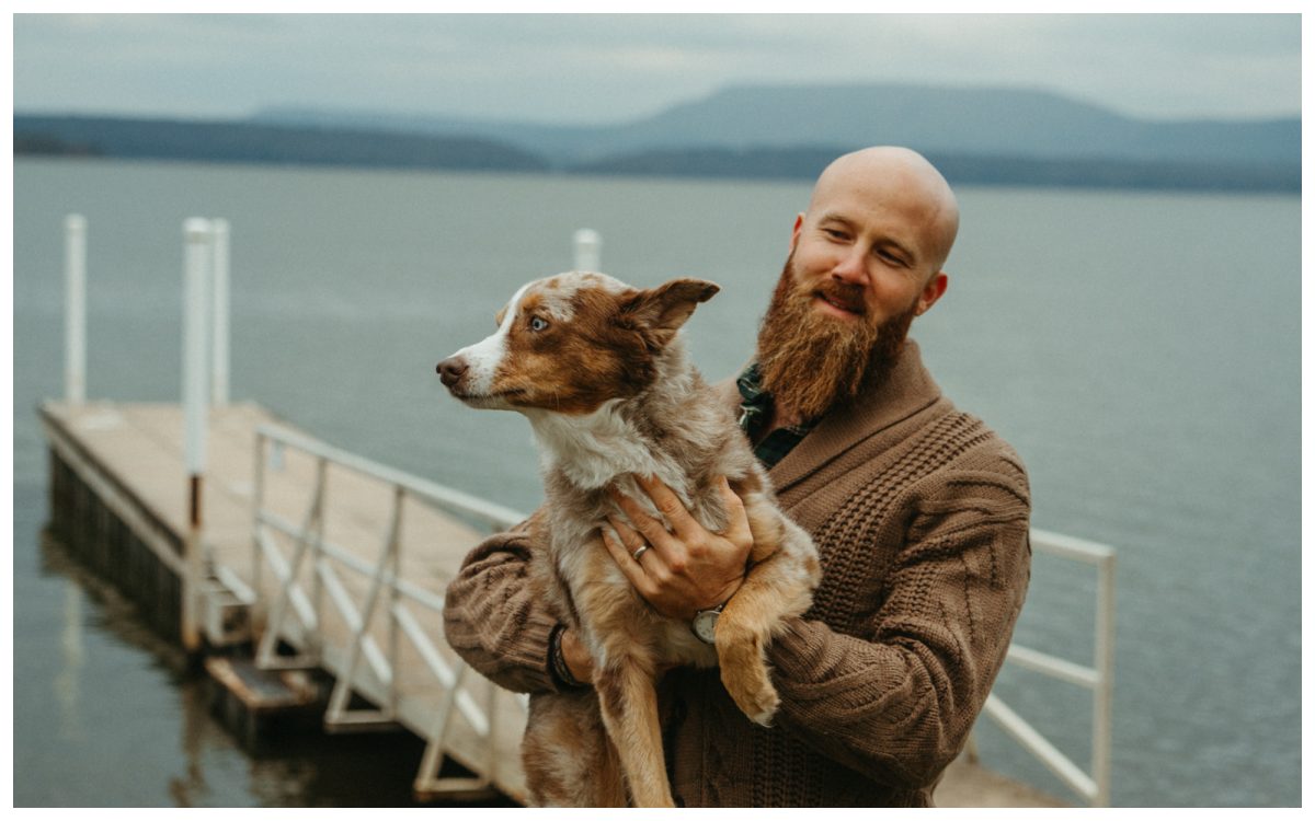 Photo of Eli Cranor on dock holding merle dog